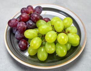 灰色の皿に盛られた赤と緑のブドウ