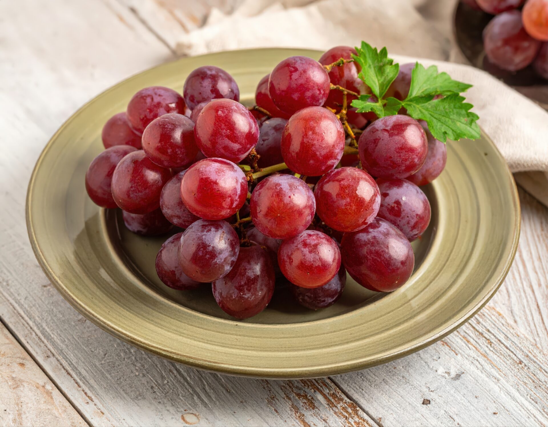 緑の皿に盛られた赤いブドウ