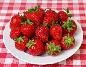 チェック柄のクロスの上の皿に盛られたイチゴ