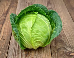 木のテーブルに置かれた丸ごとのキャベツ