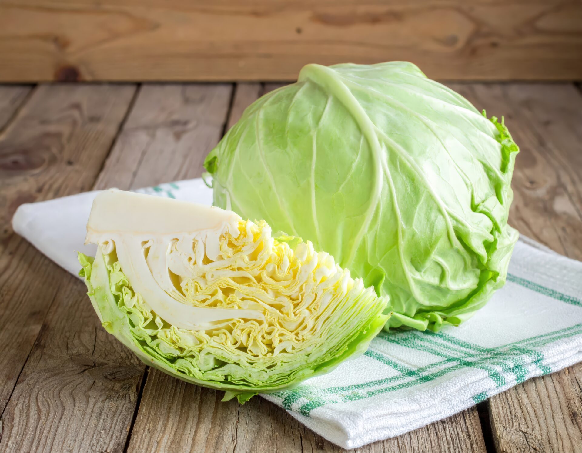 布の上に置かれた丸ごとのキャベツとカットキャベツ