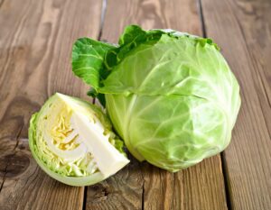 木のテーブルに置かれたキャベツとカットキャベツ