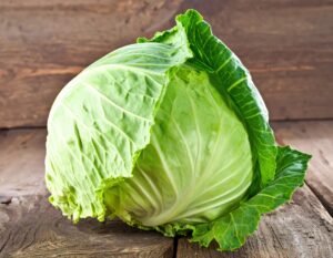 木の板の上に置かれた丸ごとのキャベツ