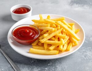 白い皿に盛られたフライドポテトと2つのケチャップ容器