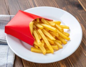 白い皿に盛られた赤いパッケージのフライドポテトとチェック柄ナプキン