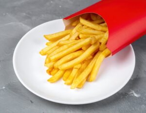 白い皿に盛られた赤いパッケージのフライドポテトとグレー背景