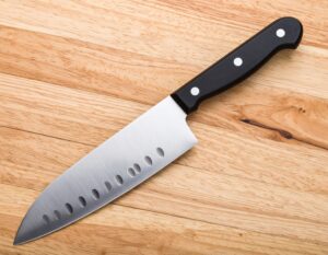 木製カッティングボードの上に置かれたグラントエッジ付き三徳包丁