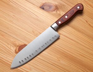 木目のカッティングボードの上に置かれた木製ハンドルの三徳包丁