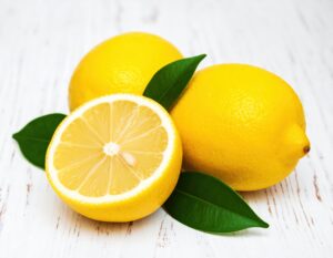 白い木製テーブルに置かれたカットレモンと丸ごとのレモン