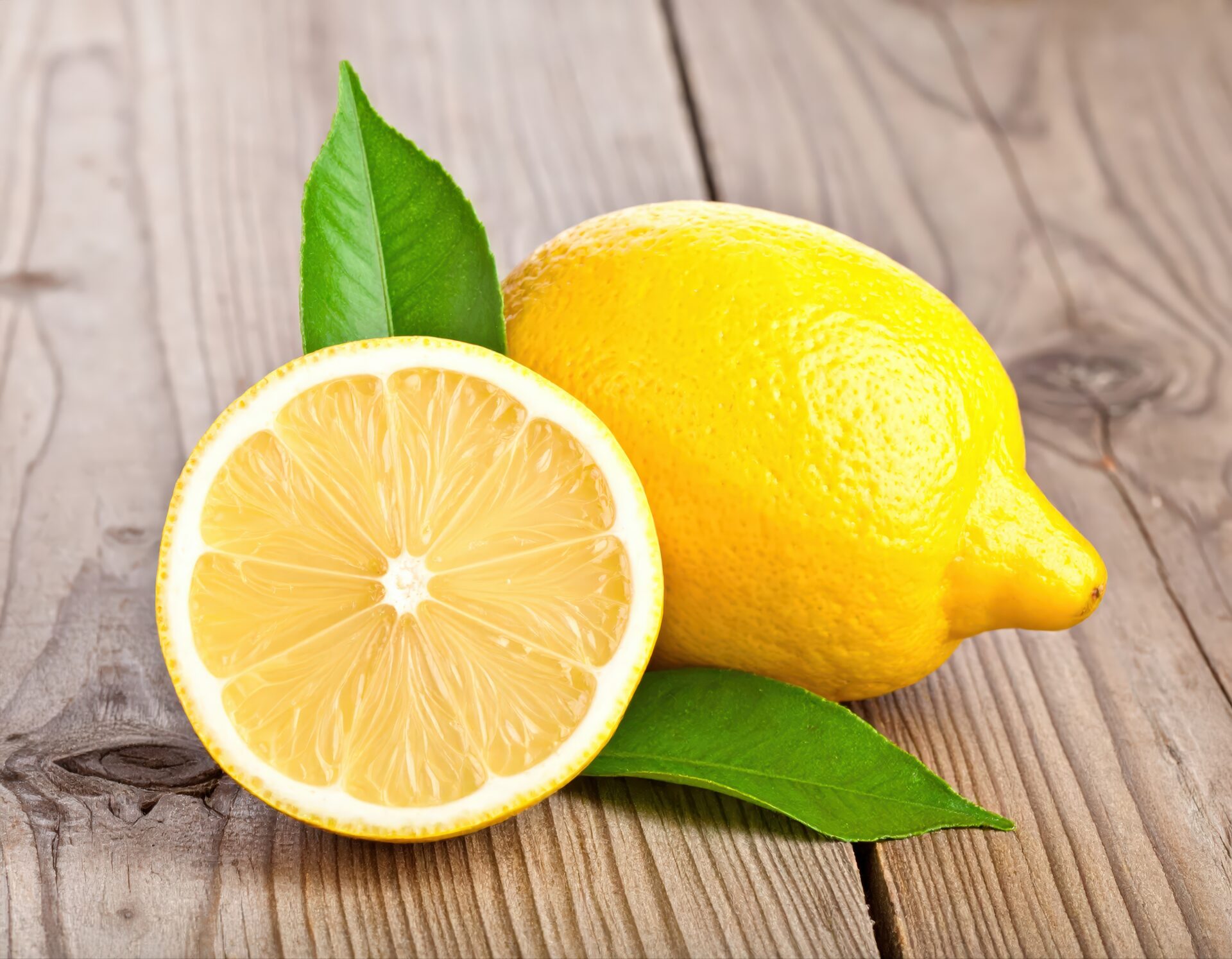 木製テーブルに置かれたカットレモンと丸ごとのレモン