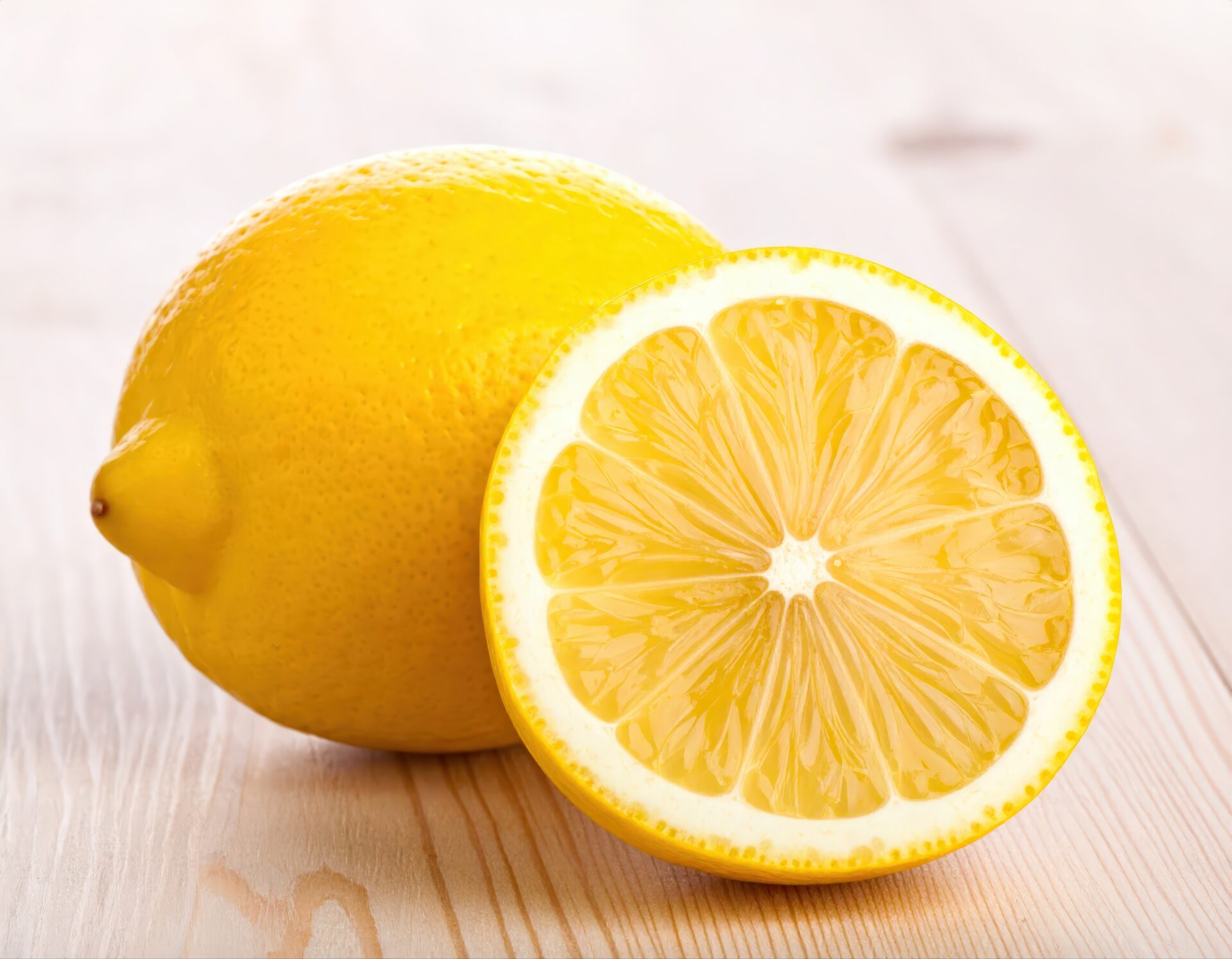 白木のテーブルに置かれたカットレモンと丸ごとのレモン