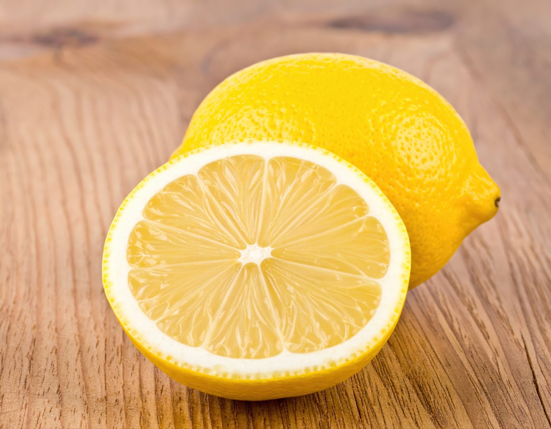 木製テーブルに置かれたカットレモンと丸ごとのレモン
