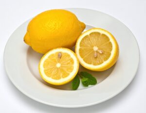 白い皿に盛られた丸ごとのレモンとカットレモン