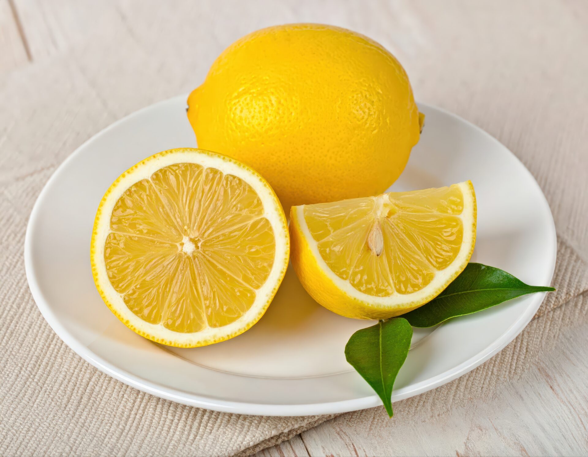 白い皿に盛られた丸ごとのレモンとカットレモンと葉