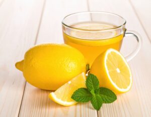 ガラスのカップのレモンティーと丸ごとのレモンとカットレモン