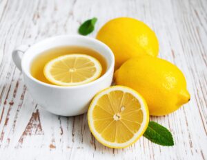 白いカップのレモンティーとカットレモンとミント