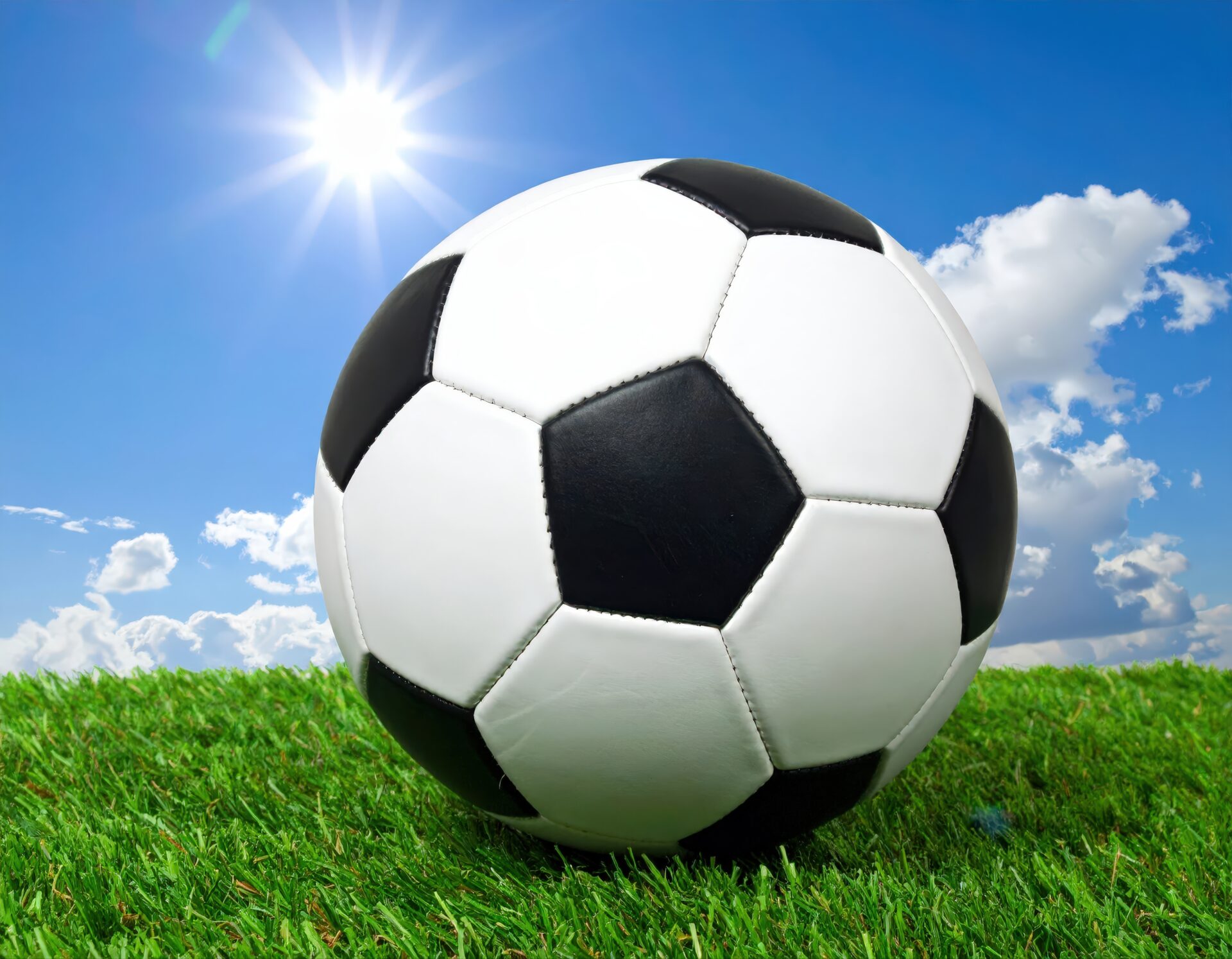 青空と芝生の上に置かれたサッカーボール