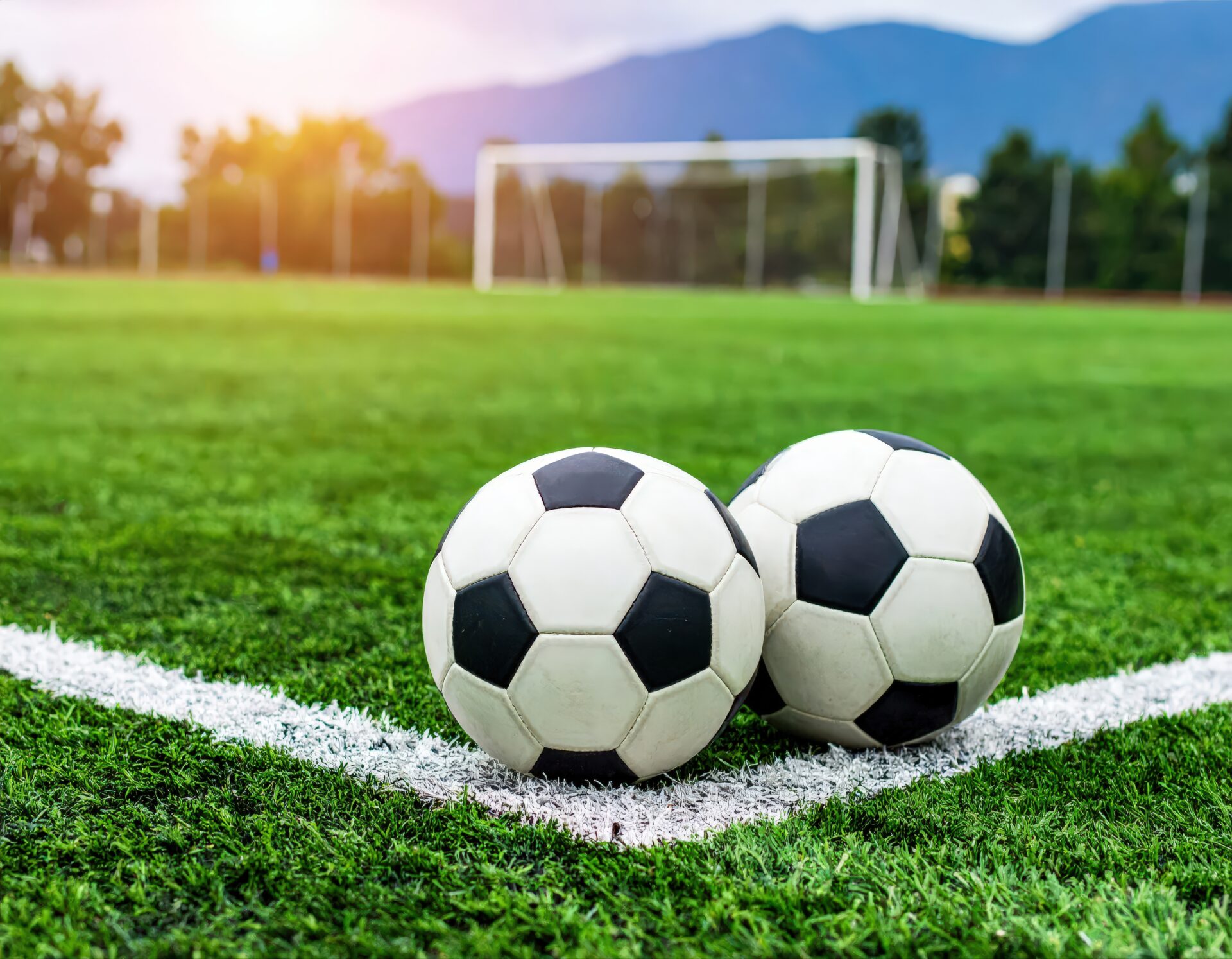 夕方のサッカーグラウンドに並んだ2つのサッカーボール