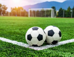 夕方のサッカーグラウンドに並んだ2つのサッカーボール