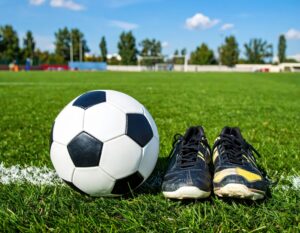 芝生の上に置かれたサッカーボールと黒いシューズ