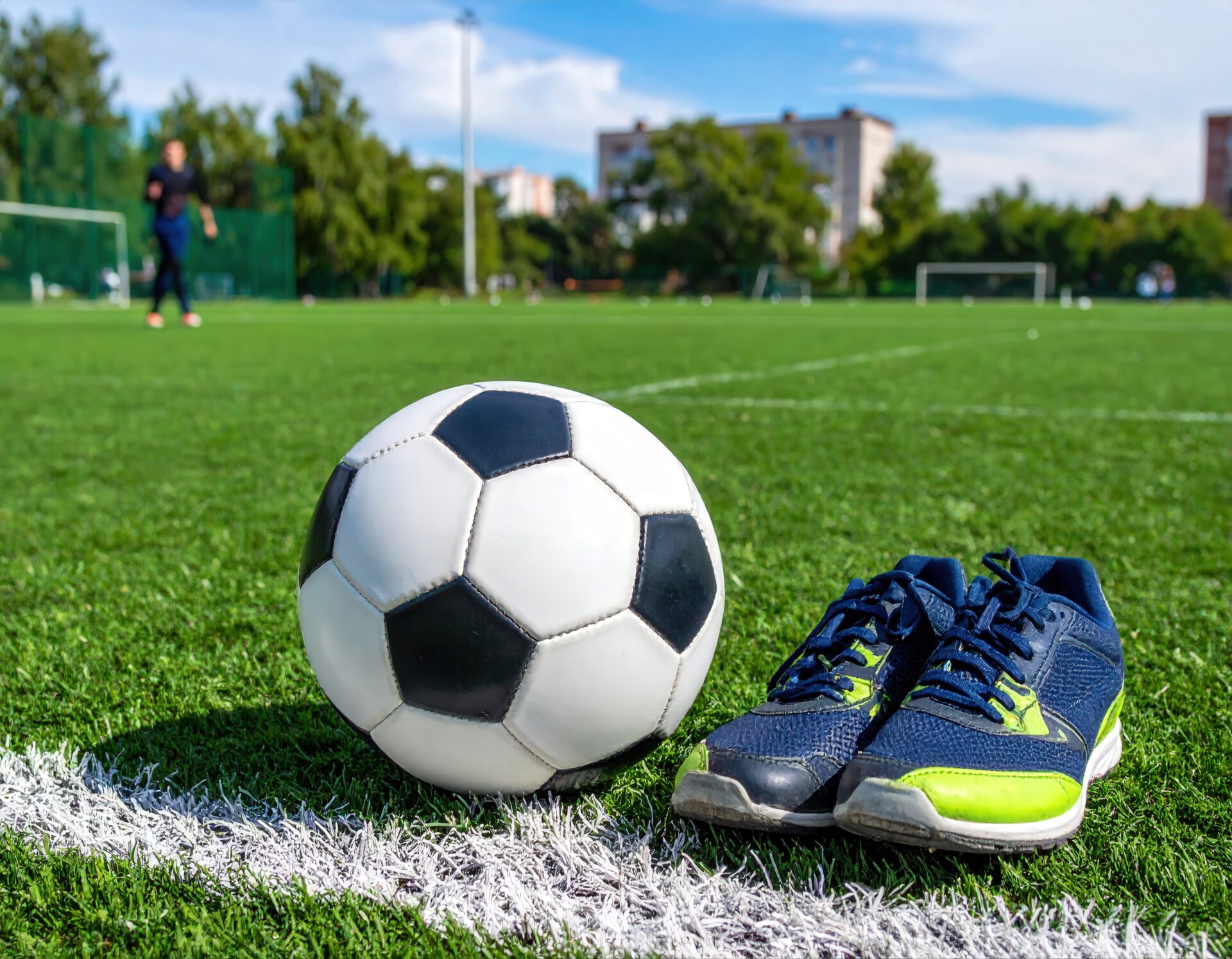 サッカーグラウンドに置かれたサッカーボールと青いシューズ