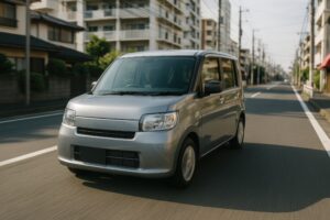 マンション街を走るシルバーの軽自動車