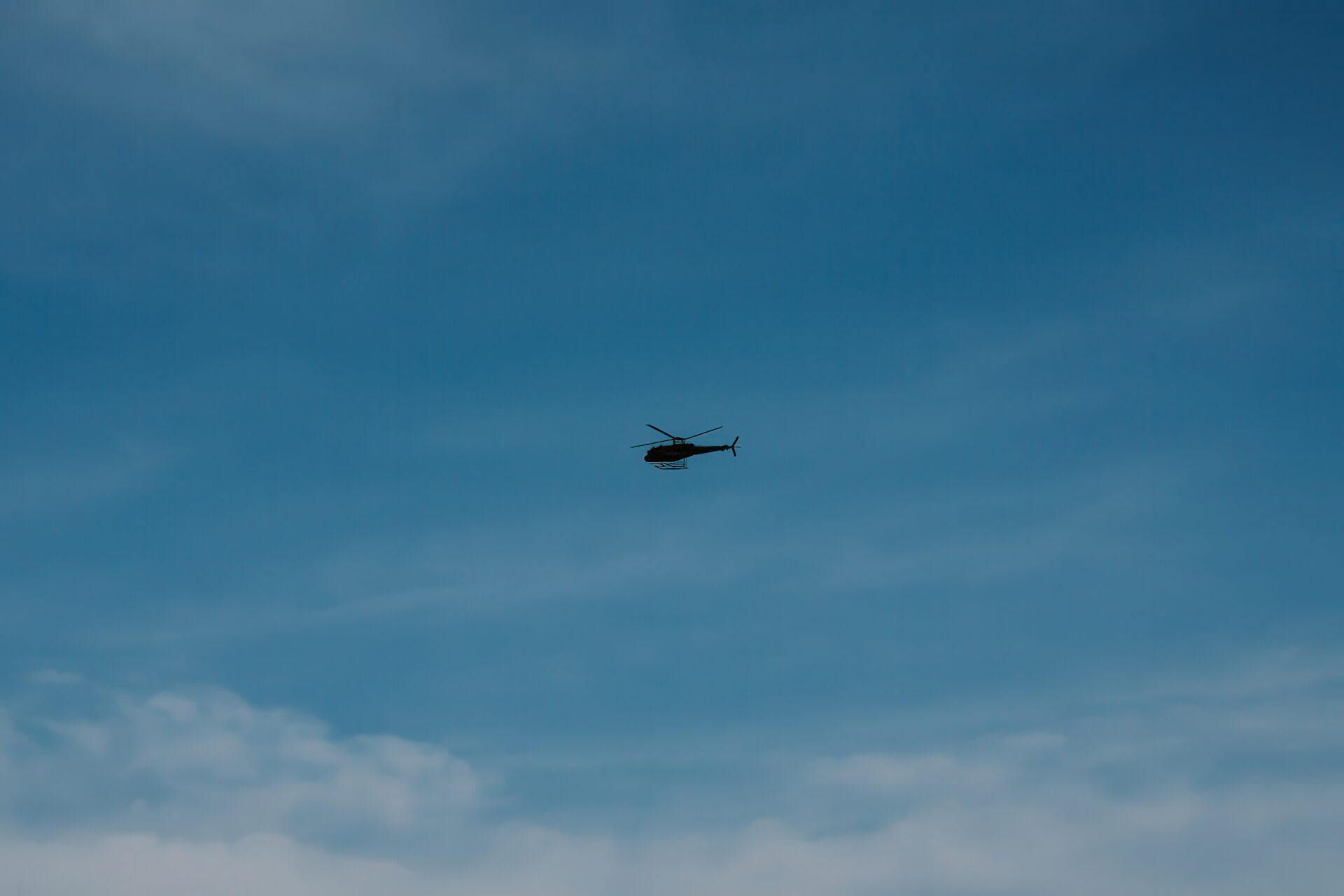 雲の広がる空を飛行する軍用ヘリコプター