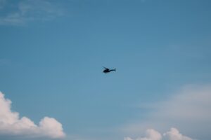 白い雲を背景に飛ぶ軍用ヘリコプターのシルエット