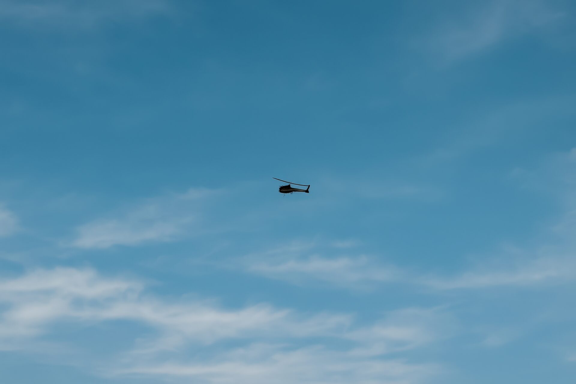 淡い雲と青空を背景に飛行する軍用ヘリコプター