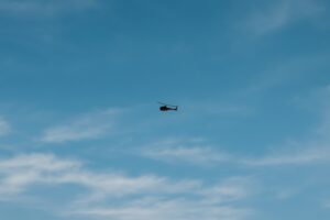 淡い雲と青空を背景に飛行する軍用ヘリコプター