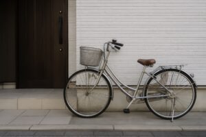 白い外壁の家の前に置かれたママチャリ