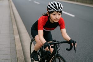 赤いジャージで舗道を走る若い女性サイクリスト