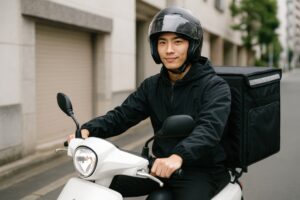 白いスクーターに乗るフードデリバリーの若者