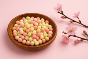 ピンク背景に置かれた雛霰と桃の花の春らしい構図