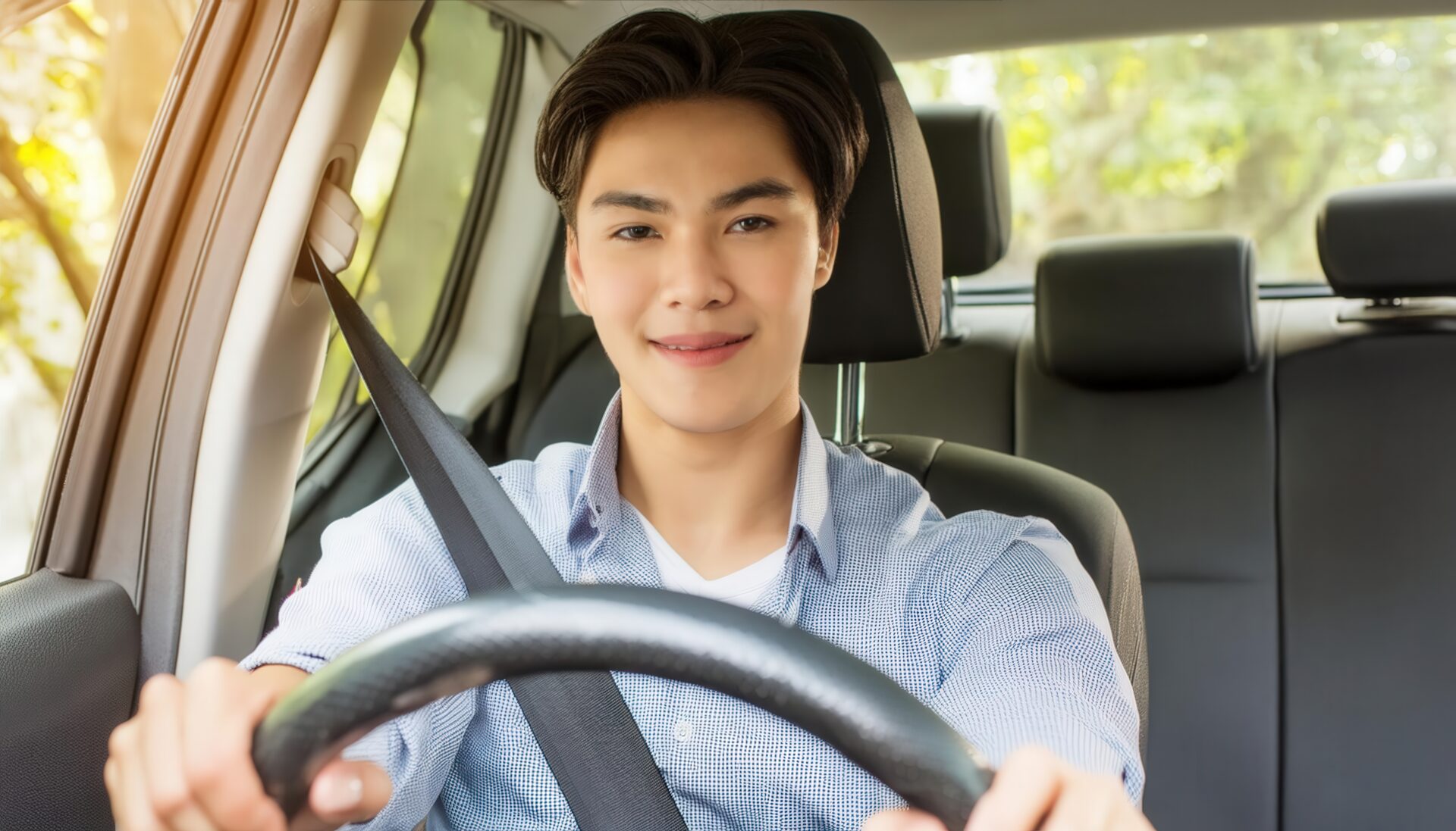 車を運転中の男性（車内・前方を向いて微笑む）