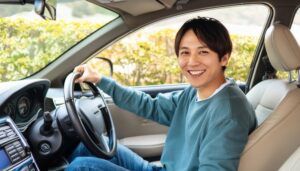 車を運転中の男性（青い服・運転席で笑顔）