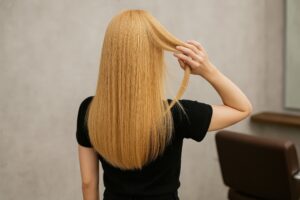 金髪のストレートヘアを見せる美容室での後ろ姿