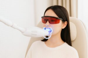 赤いメガネと開口器でホワイトニングを受ける女性