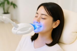 目を閉じてホワイトニングライトを当てる女性