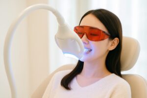 白いセーター姿でホワイトニング機器を使用中の女性