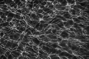 白い光が広がる黒背景の水面模様