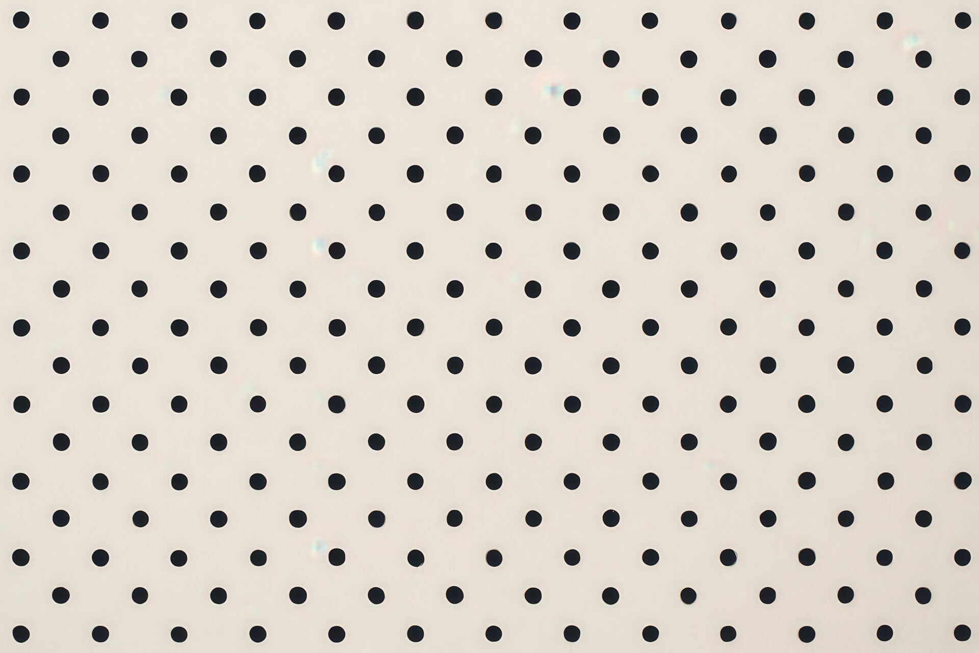 黒いドットが並ぶシンプルなベージュ背景