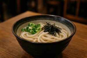 木製テーブルに置かれた刻み海苔とねぎのうどん