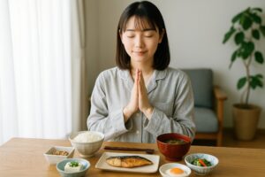 和食の朝食を前に感謝のポーズをする女性