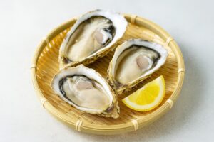 竹ざるに盛られた殻付き生牡蠣とレモン