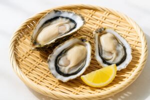 新鮮な生牡蠣とレモンを竹ざるにのせた和風盛り付け