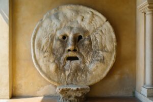 朝の光に照らされる真実の口の石像と背景の壁面