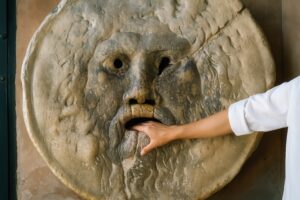 真実の口に手を入れている白い服の観光客の腕