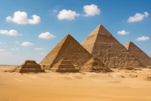 雲の浮かぶ青空と砂漠に立つギザのピラミッド群
