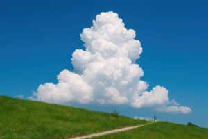 夏の青空にそびえる入道雲と草原の小道
